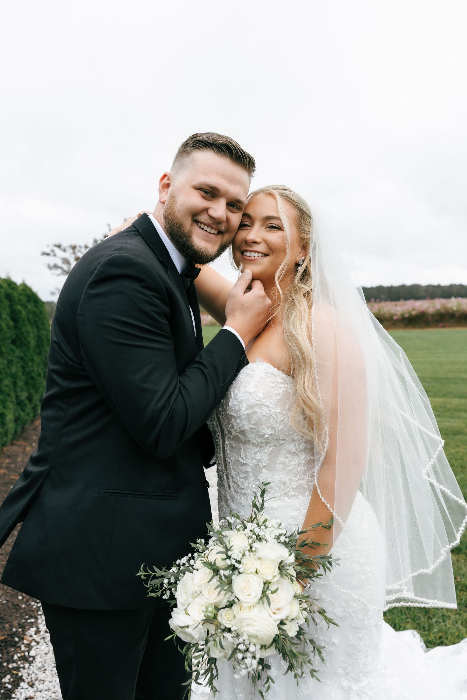 A joyful wedding couple shares intimate moments in a series of black and white outdoor portraits with white floral bouquet.