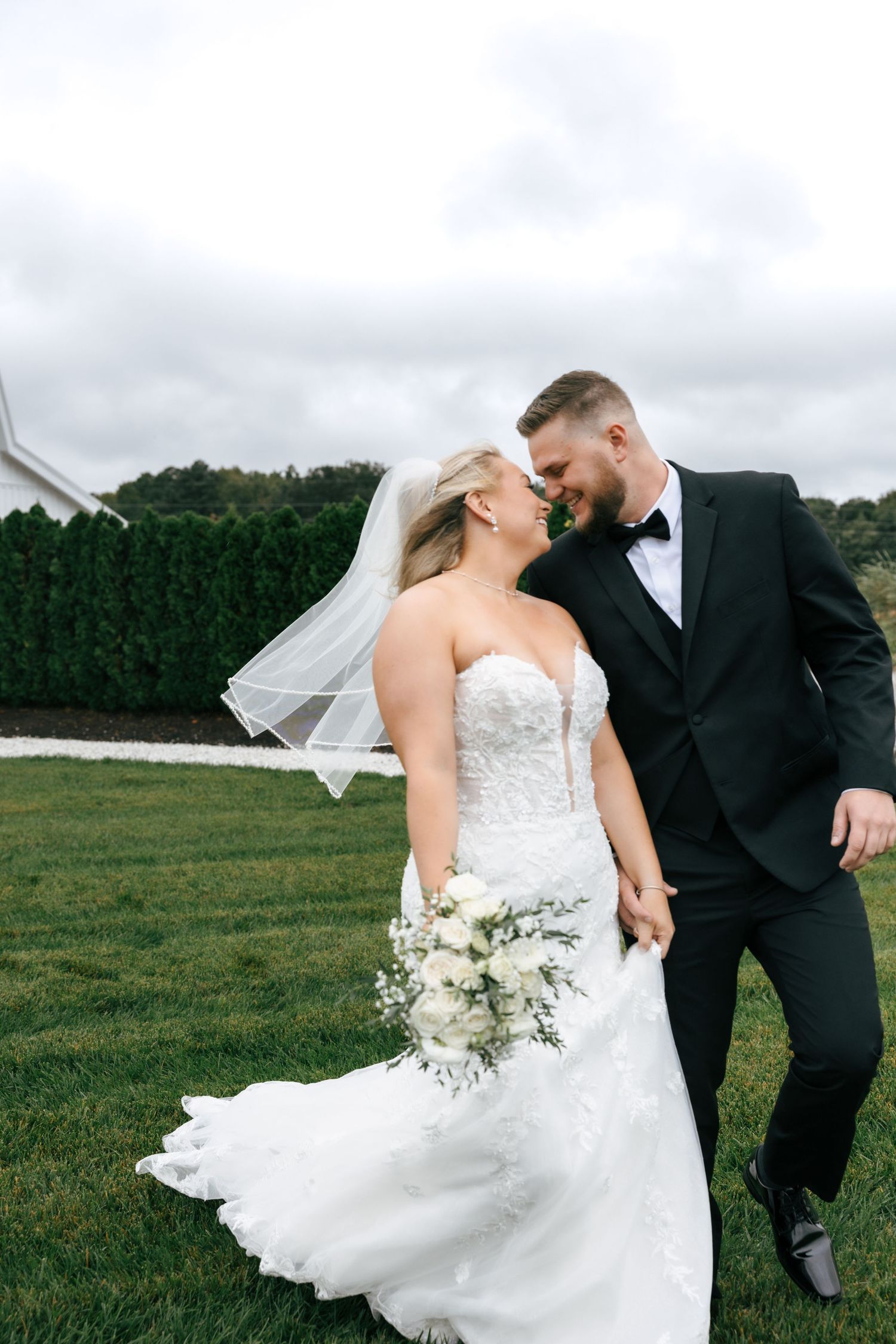 Romantic wedding couple dancing and twirling in an open field with flowing white dress and veil.