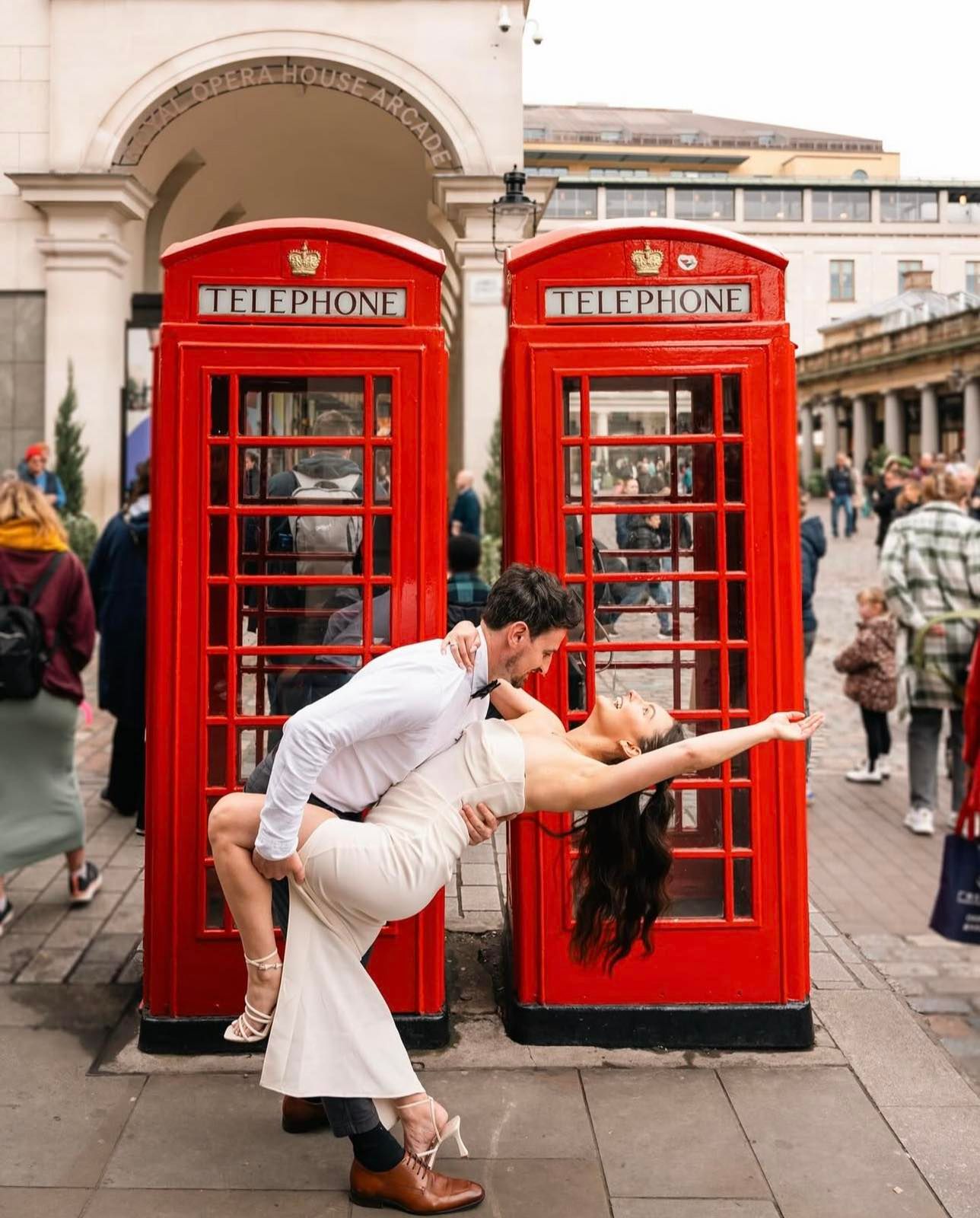 Creative wedding photo of couple posing dramatically in front of iconic red London phone booths.