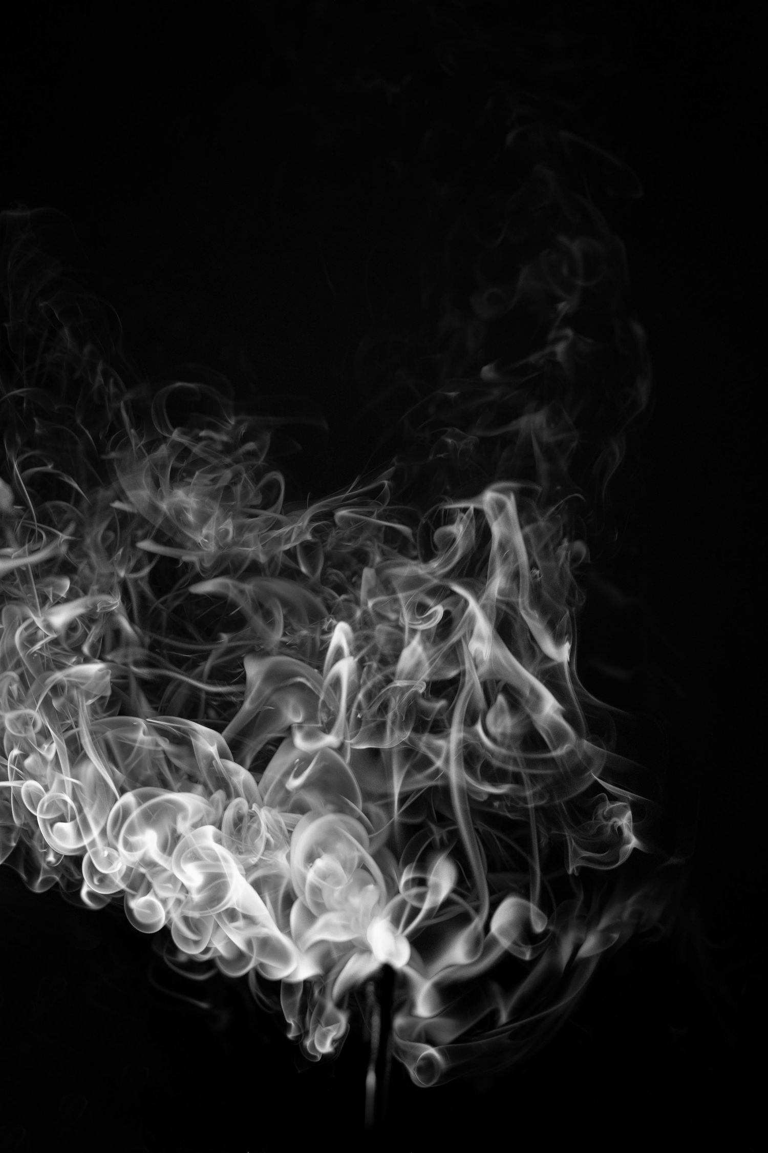 White smoke swirling in abstract patterns against a black background, creating a sense of motion and ethereal texture.