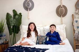 Indoor lifestyle photo on white bed with boho wall decor and houseplants.