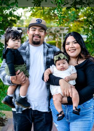 Casual outdoor family portrait session under green leafy trees.