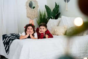Festive family portrait session with macrame backdrop and indoor plants near a Christmas tree.