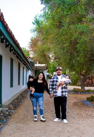 Group poses along white stucco walkway with green shutters and stone accents.