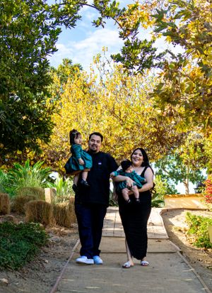 A family standing together on a garden path surrounded by autumn foliage and bright yellow trees.
