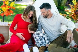 Fall-themed maternity photo with teepee, pumpkins and autumn leaves as decorative elements.