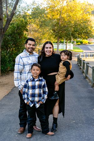 Playful outdoor photo session on paved path with coordinated outfits in autumn setting.