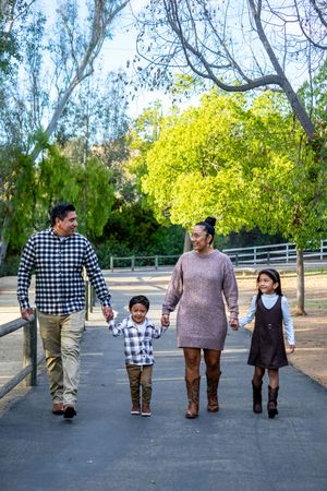 Group walking together on paved path wearing coordinated outfits with trees and fence in background.