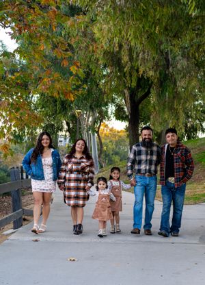 Family members walk along a path wearing coordinated casual outfits with plaid patterns.