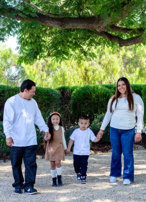 Family walking together on gravel path under lush green trees.