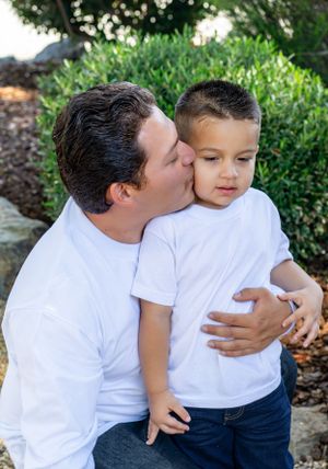 Tender family moments captured in garden setting with white shirts.