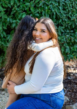 Joyful embraces captured against leafy green garden backdrop.