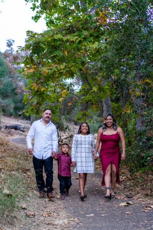 A family walks together on a nature trail surrounded by fall foliage.