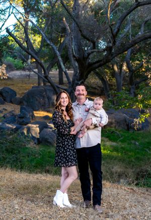 Natural outdoor family portrait session among oak trees at golden hour.