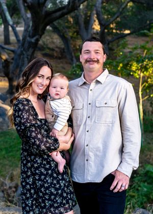 Family portrait session in wooded setting with dappled sunlight.