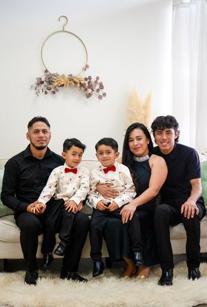 Family portrait on white couch with minimalist wall decor and neutral color scheme.