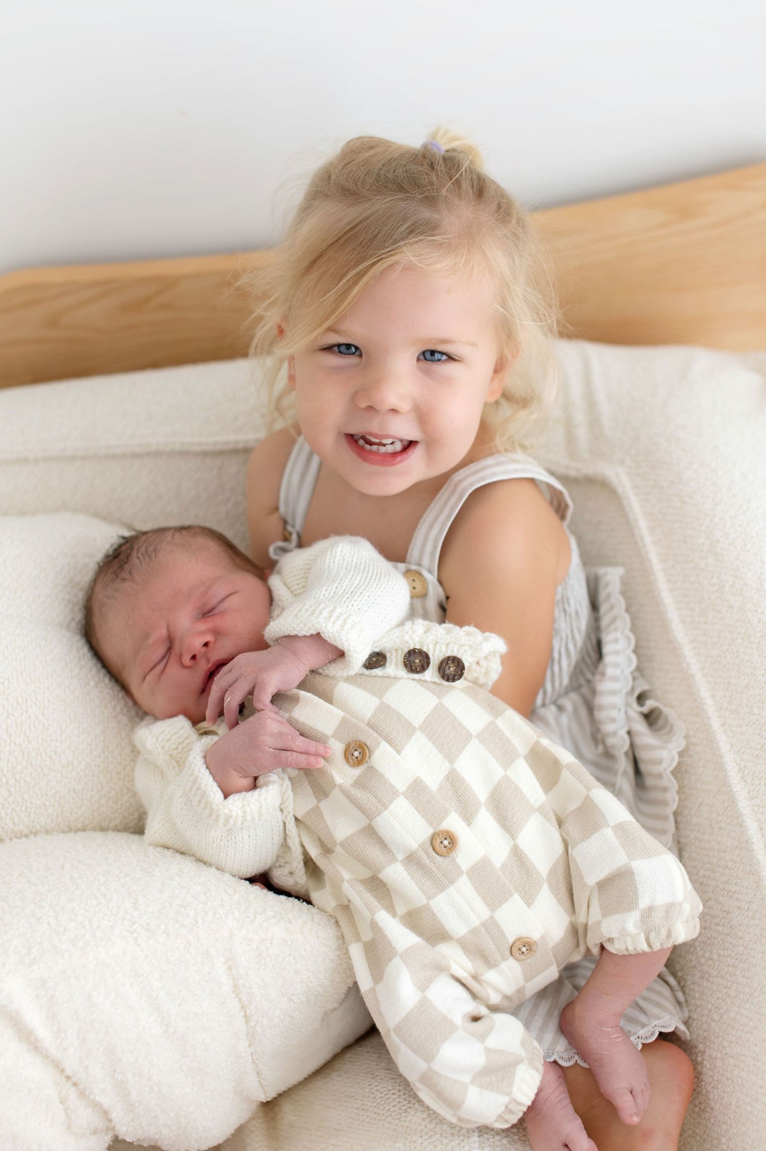 A tender moment between parent and baby lying together on white bedding.