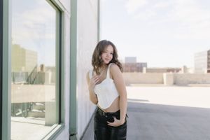 Casual portrait against white wall with urban rooftop views.