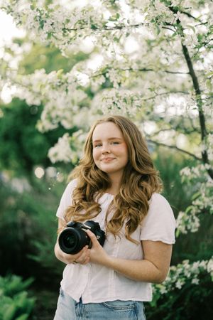 Spring portrait taken under blooming white cherry blossoms with natural lighting and soft bokeh effect.