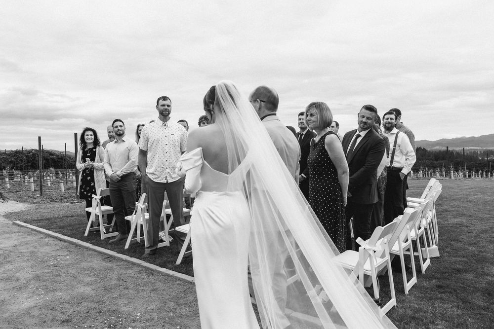 Wedding guests seated in white chairs at an outdoor ceremony with mountain views.