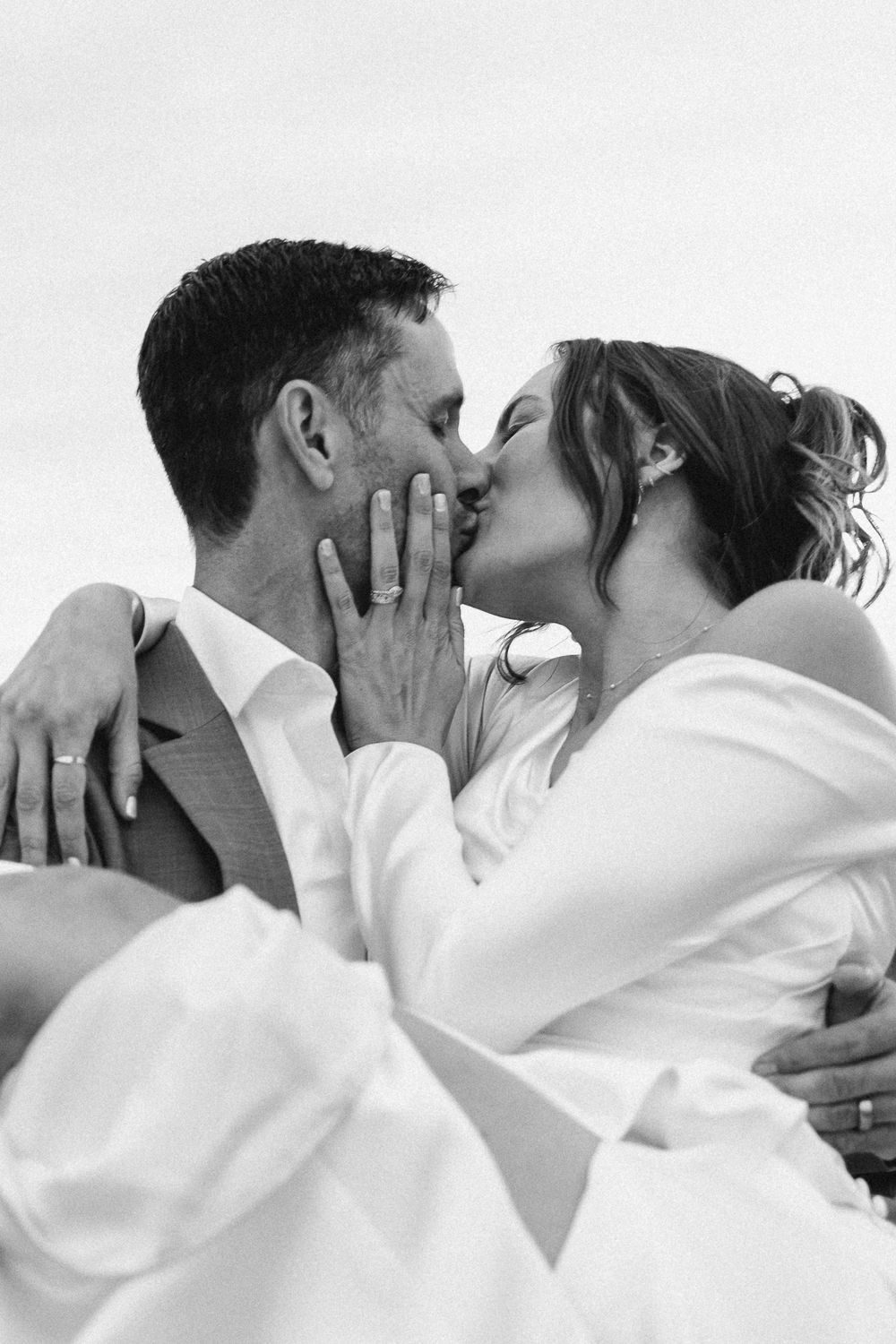 An intimate black and white portrait of newlyweds sharing a romantic kiss.