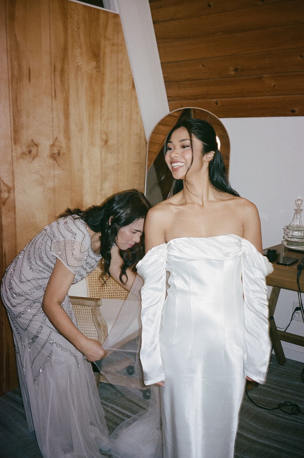 A wedding dress fitting moment captured in a rustic wooden interior.