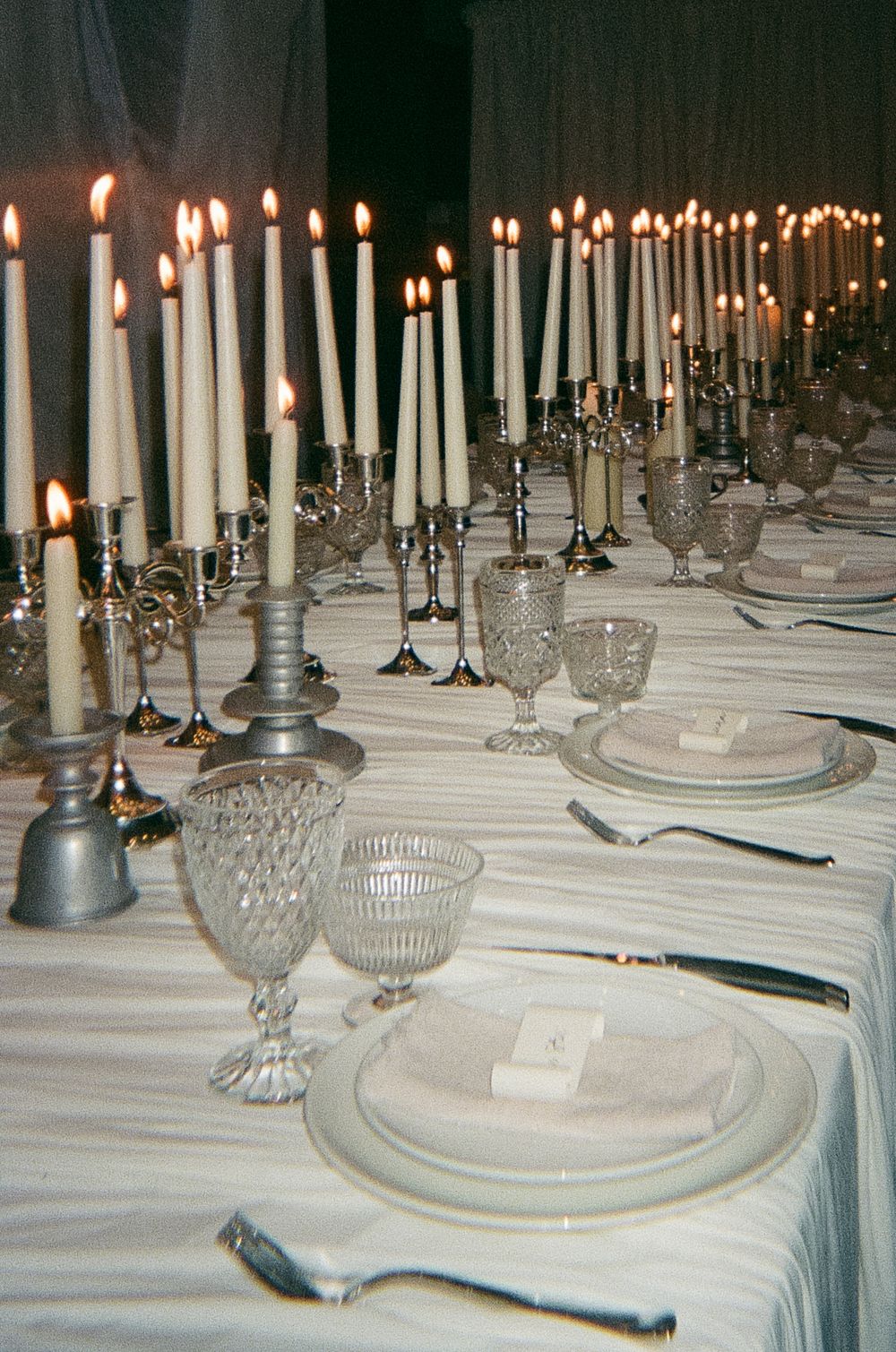 Elegant wedding table setting with lit white candles and crystal glassware.