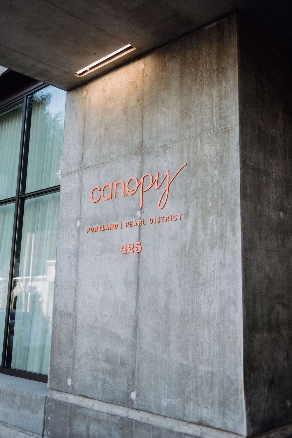 Modern concrete building exterior with orange signage and glass windows.