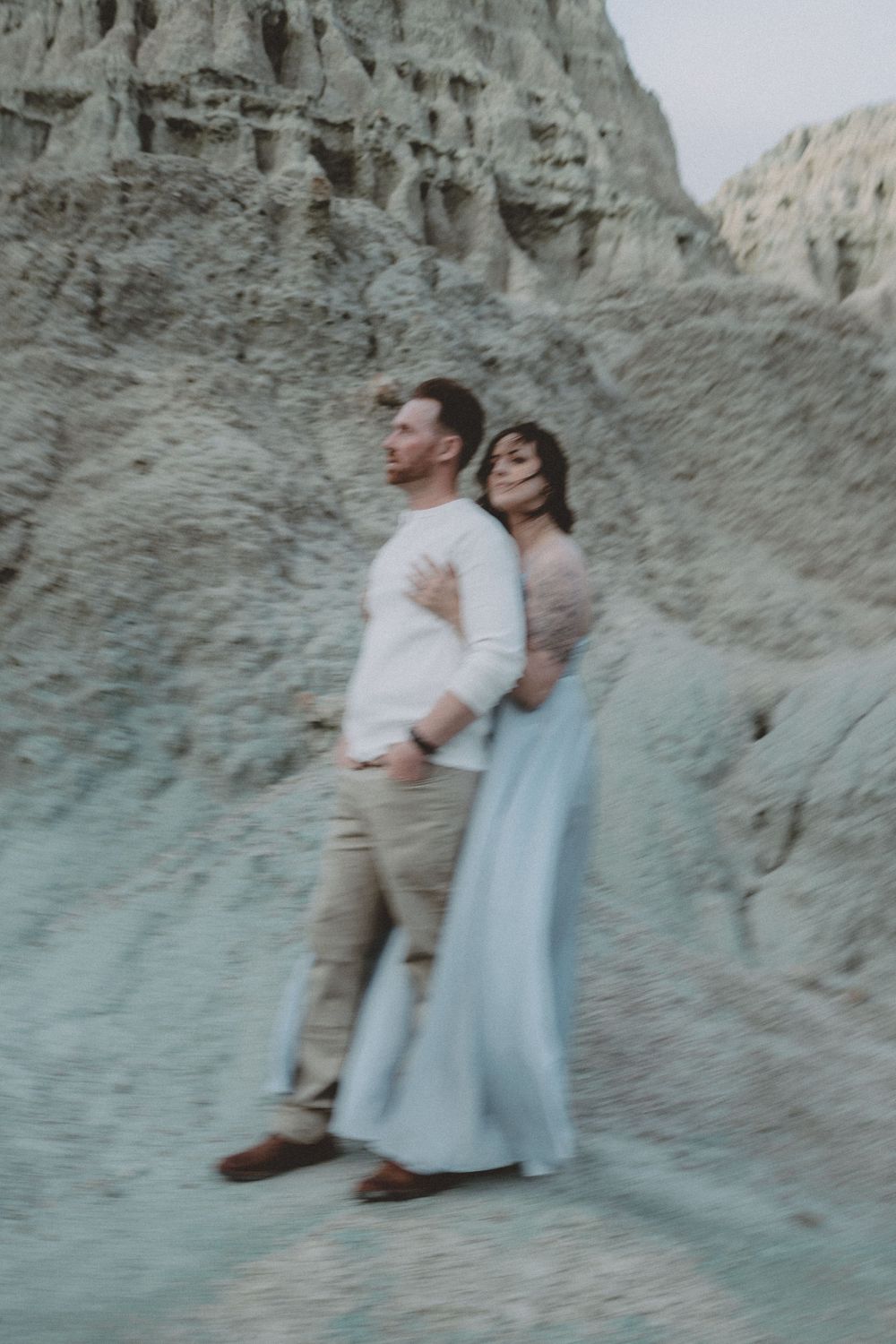 A couple poses elegantly against towering desert rock formations.