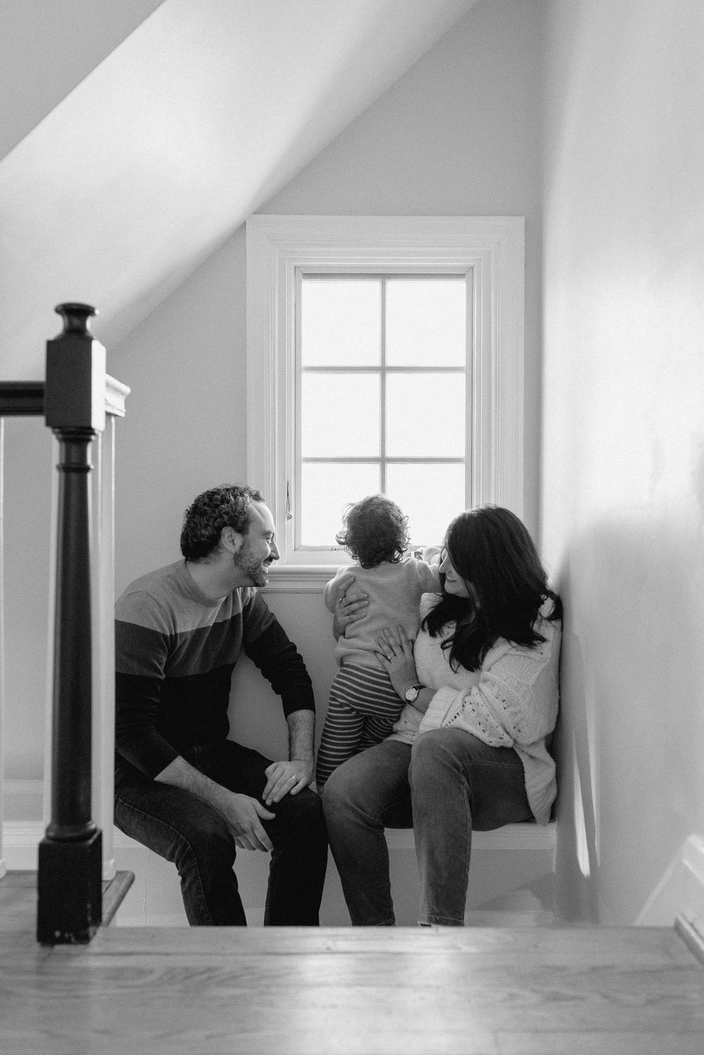 A family sitting together by a window in their home, sharing an intimate moment.
