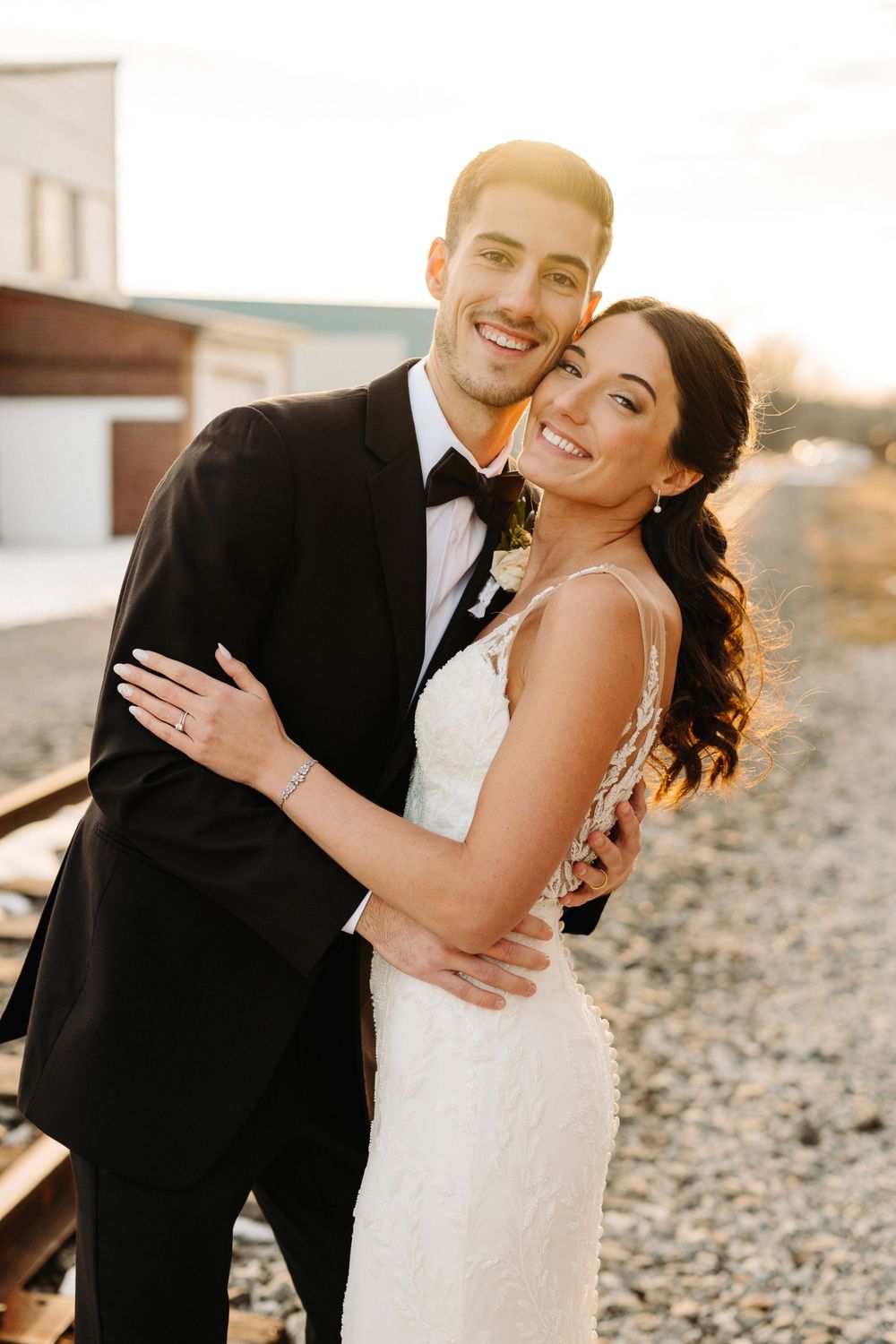 Sunset portrait of newlyweds in formal attire smiling together.