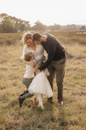 A loving family shares an intimate moment together in a golden sunlit field at sunset.