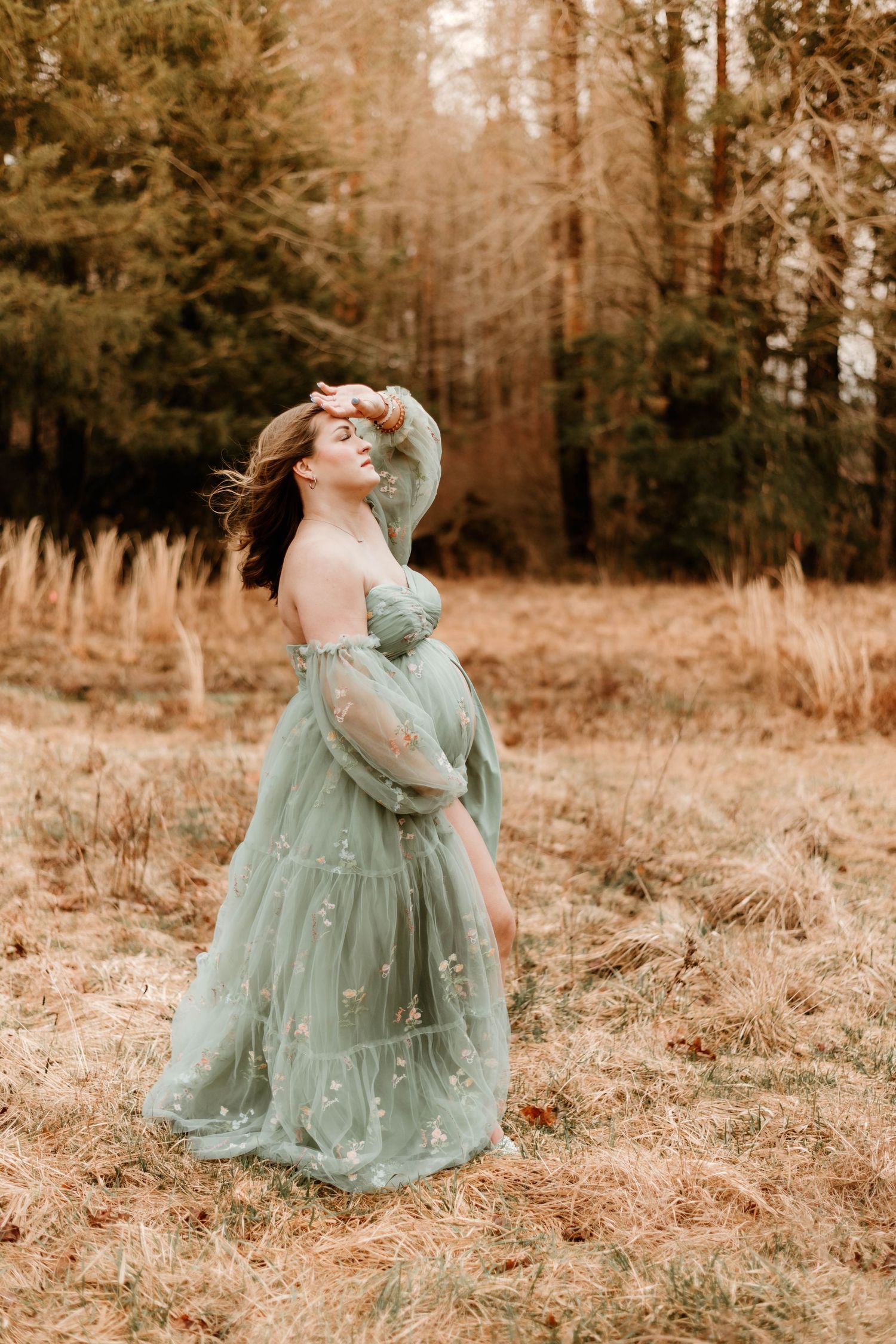 A dreamy portrait of a woman in a flowing mint green gown standing in a sunlit autumn field.