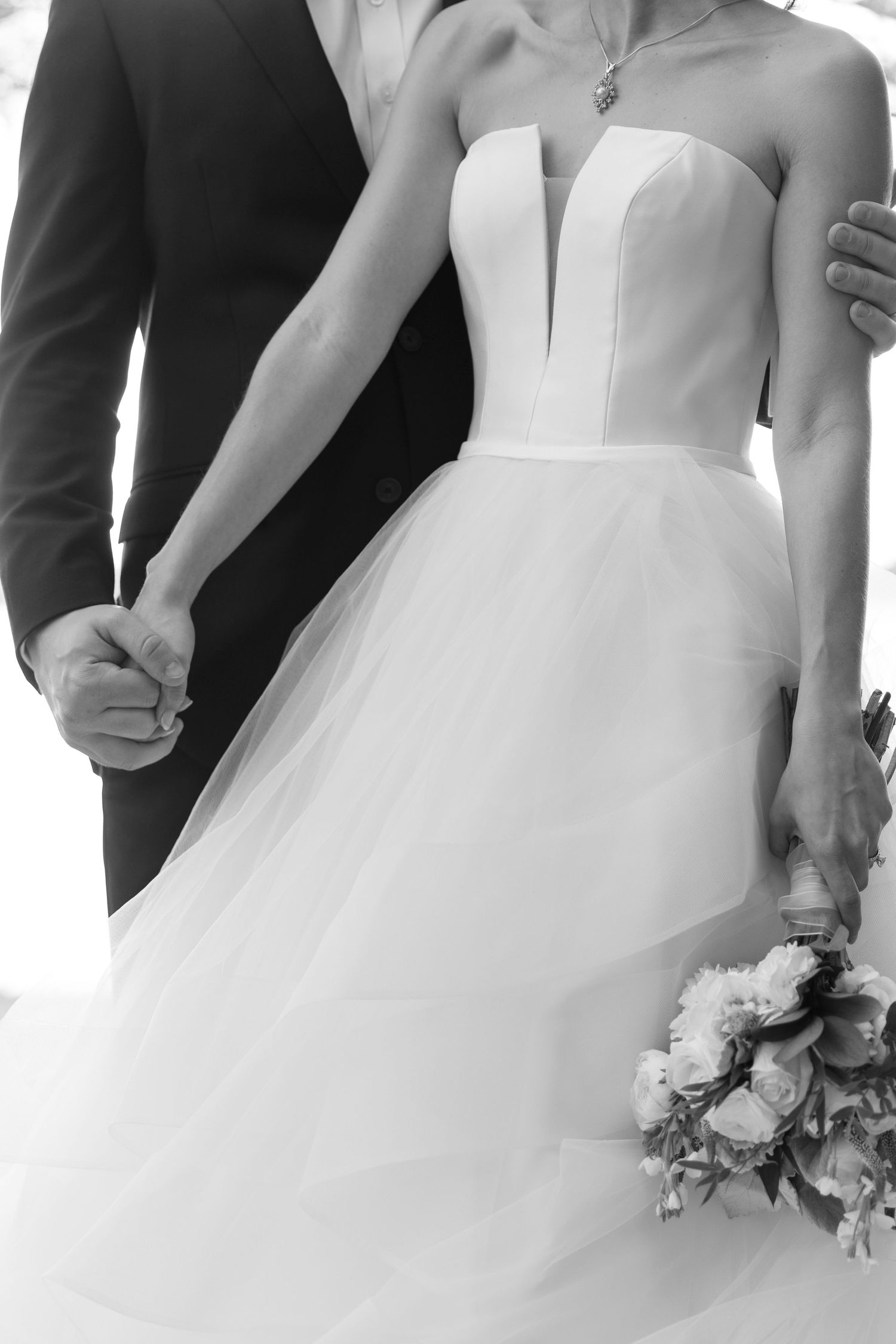 Close-up details of white wedding dresses and bouquets in an elegant outdoor setting.