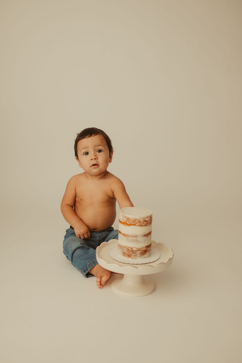 Baby boy looks at camera curiously during first birthday cake smash photos in Clarksville, Tennessee photography studio.