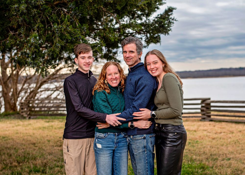 A group of people standing together outdoors with a scenic coastal landscape in the background.