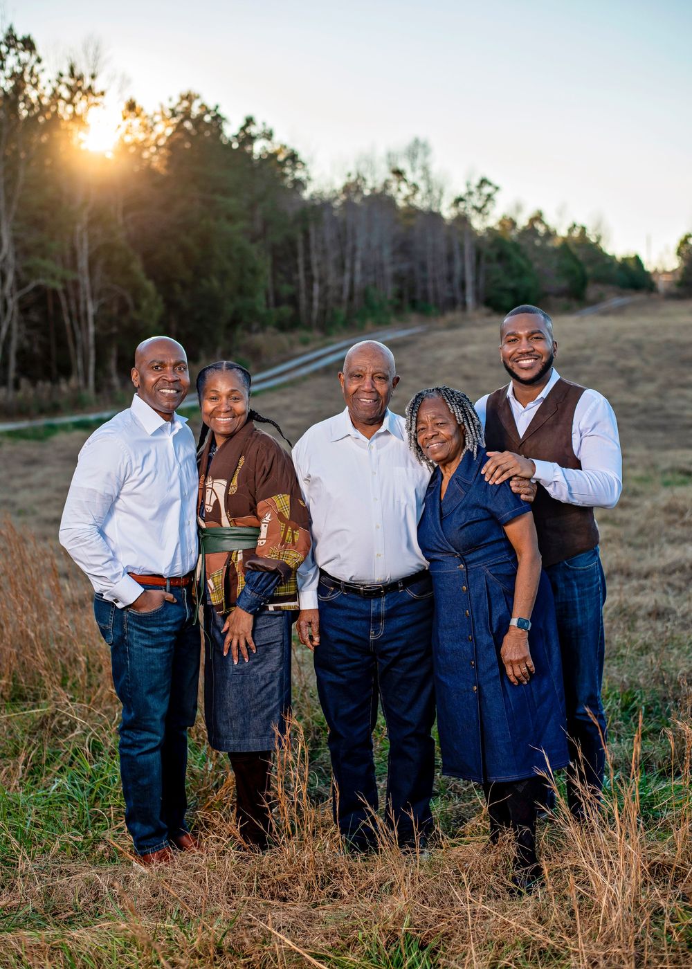 A group poses together outdoors in coordinated denim and white outfits during golden hour.