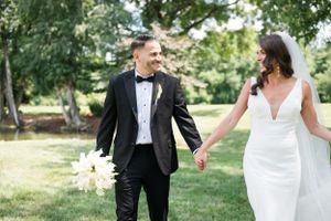 Wedding couple walking through a lush green garden on their special day.