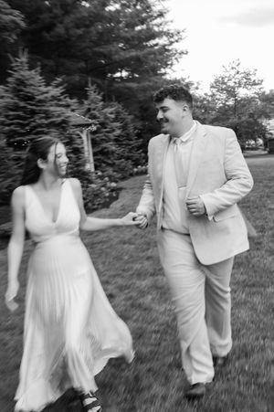 A joyful couple dances and twirls across a grassy field in black and white. the woodwinds Branford CT