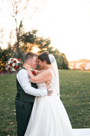 A romantic outdoor wedding moment captured during golden hour with red floral bouquets. the woodwinds Branford CT