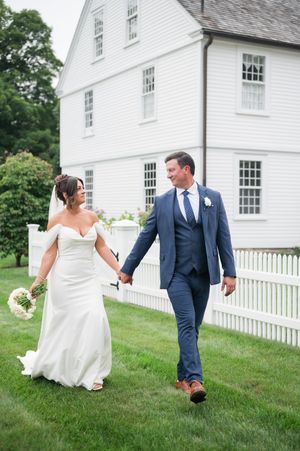 A couple walks playfully on the lawn in front of a classic white New England style house. Smith Farm Garden CT