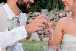Close-up of champagne glasses clinking during an outdoor wedding celebration. Kalmia Garden at Gastler Farm