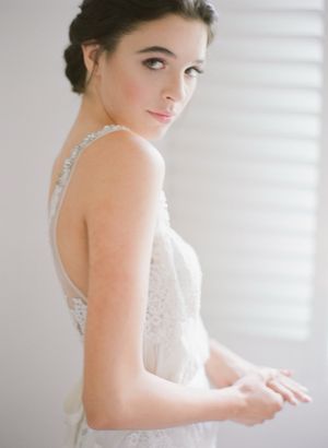 Elegant bride in lace wedding gown posing with soft natural light bridal portrait.