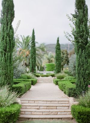 Formal Italian garden wedding venue with cypress trees and stone pathway leading to altar.