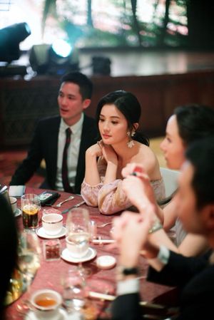 Elegant woman in off-shoulder gown seated at a formal dinner table during a wedding reception.