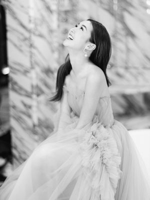 Joyful bride in a strapless tulle gown laughing in a black and white portrait photo.
