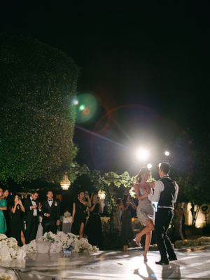 Bride and groom share their first dance on an illuminated outdoor dance floor at night.