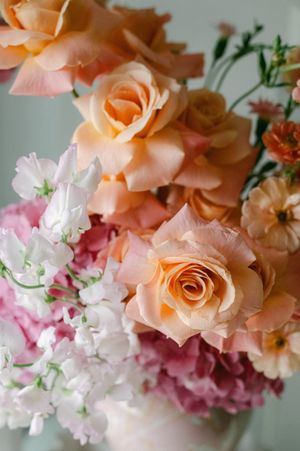 Elegant wedding bouquet featuring peach roses, pink hydrangeas, and white sweet peas.