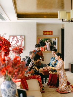 Traditional Chinese tea ceremony with family in ornate embroidered wedding attire indoors.