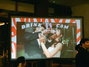 Couple featured on drink cam screen sharing a fun moment at wedding reception.